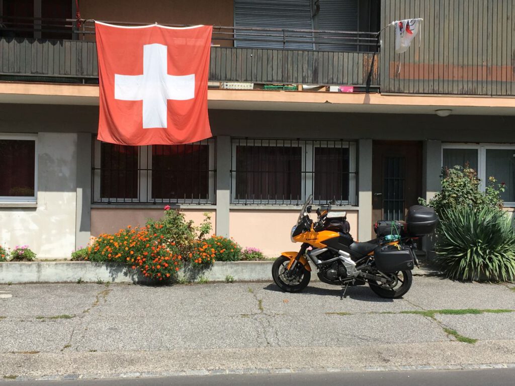 Route des Grandes Alpes – allein unterwegs zwischen Pässen, Hitze und Sehnsucht 17 22 Motorrad und Schweizer Flagge bei der Unterkunft am Lago di Piano