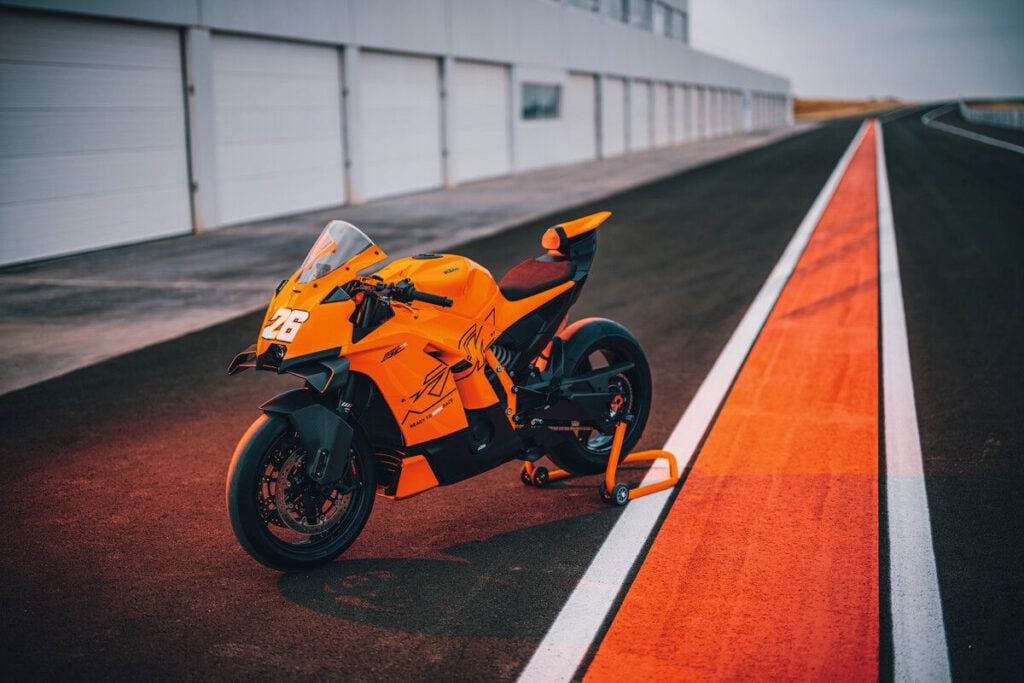 KTM 990 RC R 2026 – Supersportlicher Adrenalinträger für Straße und Rennstrecke 7 KTM 990 RC R 2026 orange Seitenansicht schräg auf Ständer und Rennstrecke