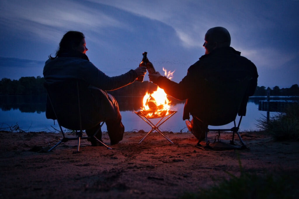 Motorrad-Camping - Erzgebirge (Paar beim Feierabendbier am nächtlichen Lagerfeuer)