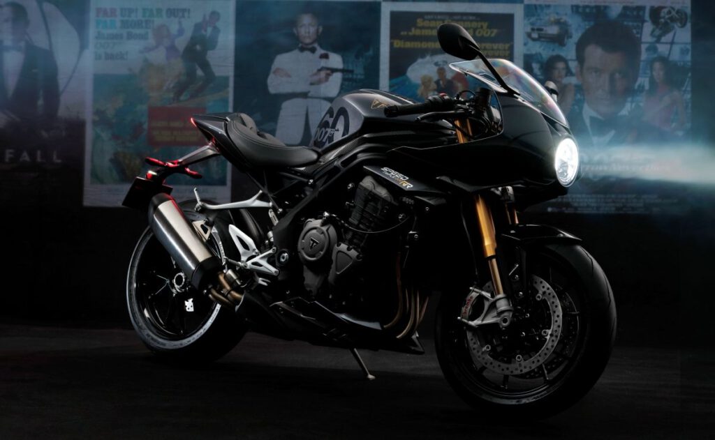 Triumph Speed Triple 1200 RR Bond Edition Seitenansicht vor Bond-Plakaten